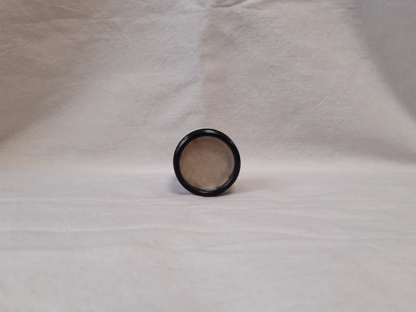 Jar of face mask labeled 'Hyd' on a gray background and opened to see contents
