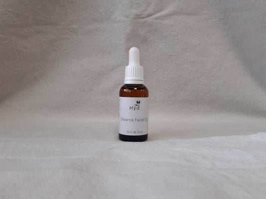Bottle of Hyd facial oilon a textured gray background