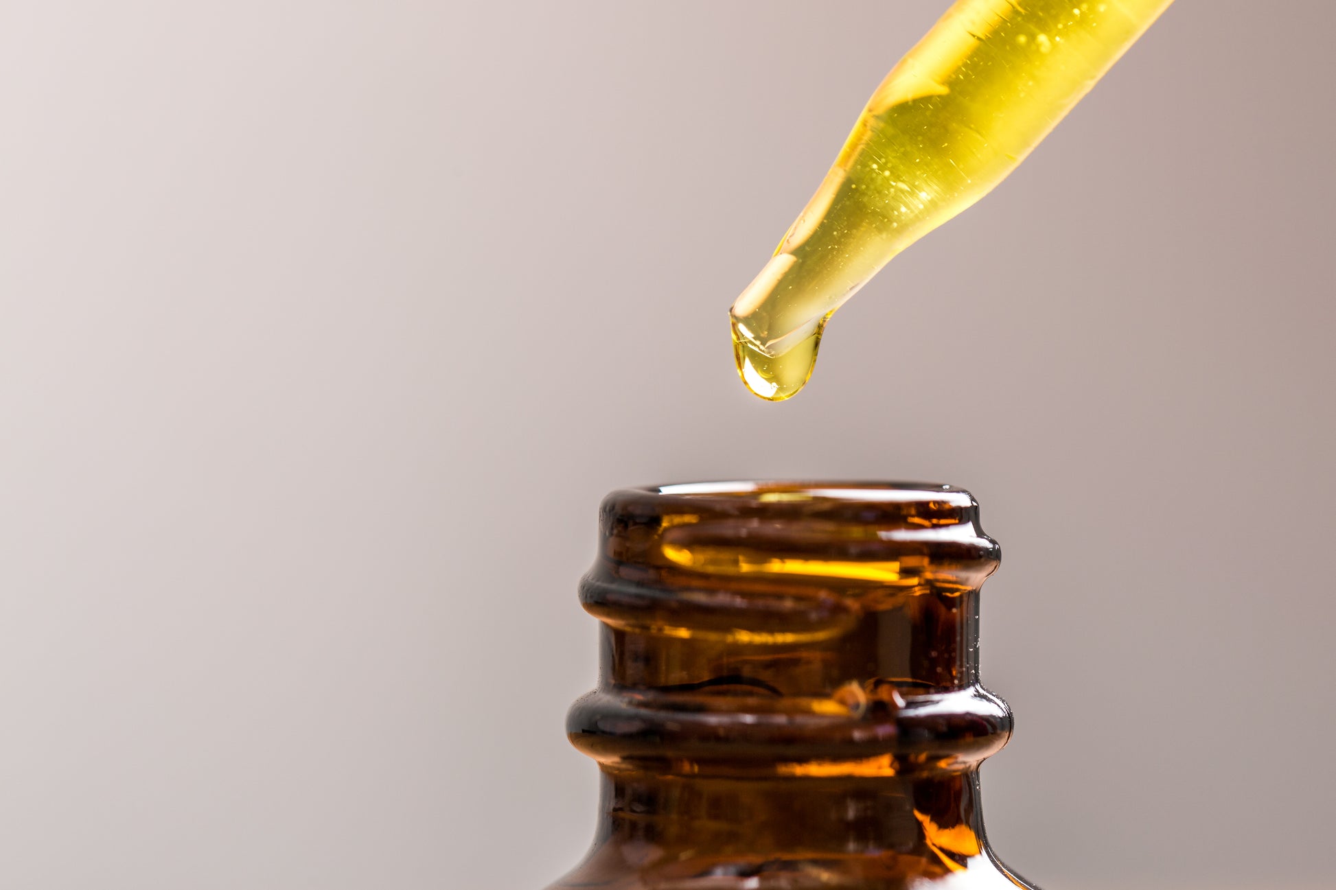 Balance Facial Oil dripping into an amber glass jar